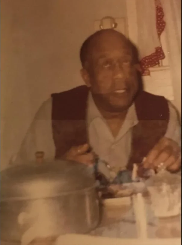 A warm archival photograph of a family elder seated at the table for a celebration meal