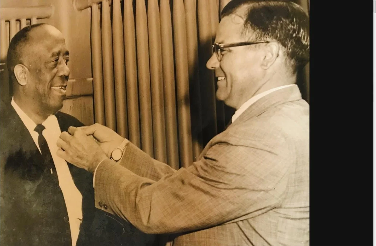 An archival photograph of a family member receiving an honor pinned to his lapel