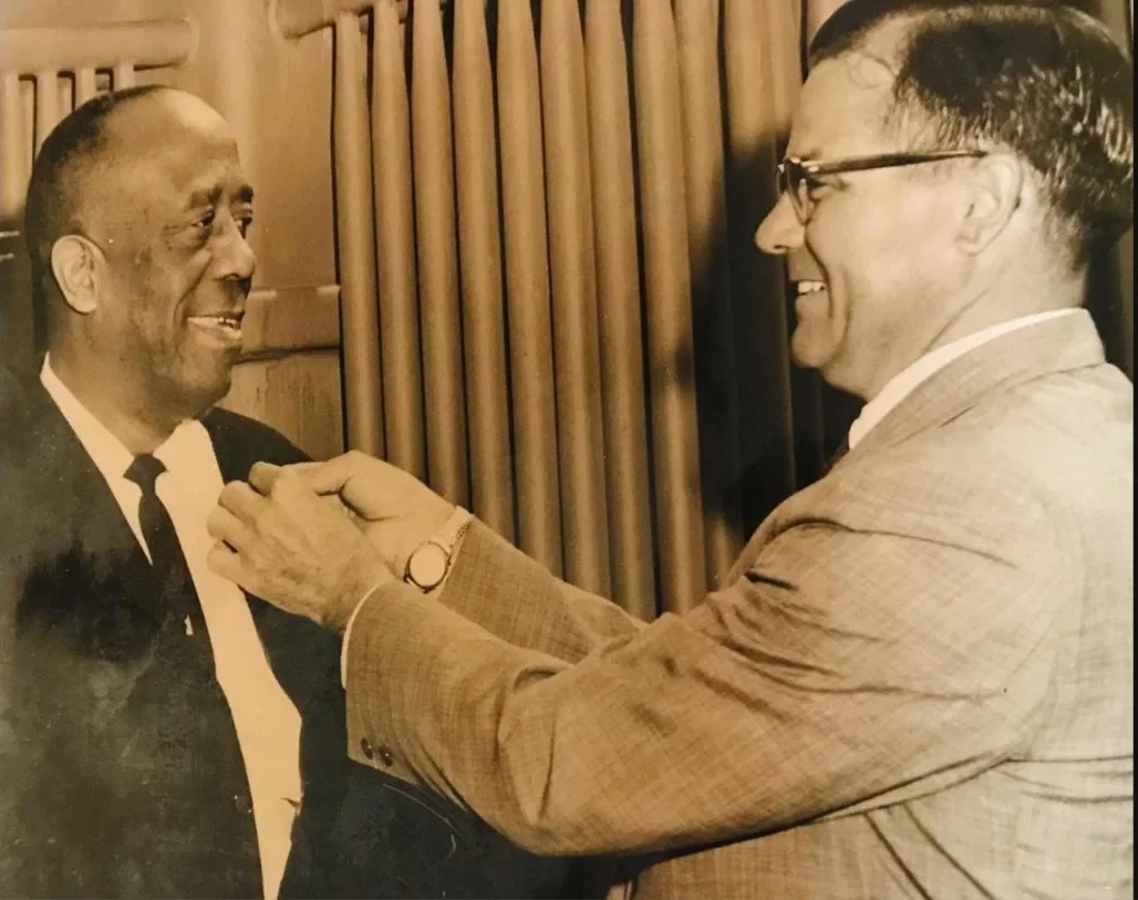 An archival photograph of a family member receiving an honor pinned to his lapel