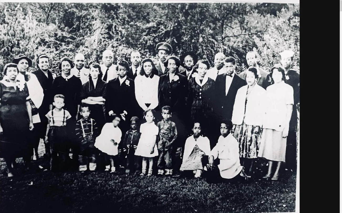 A mid-century black and white photograph of the Cash-Neill family gathered outdoors in their Sunday best