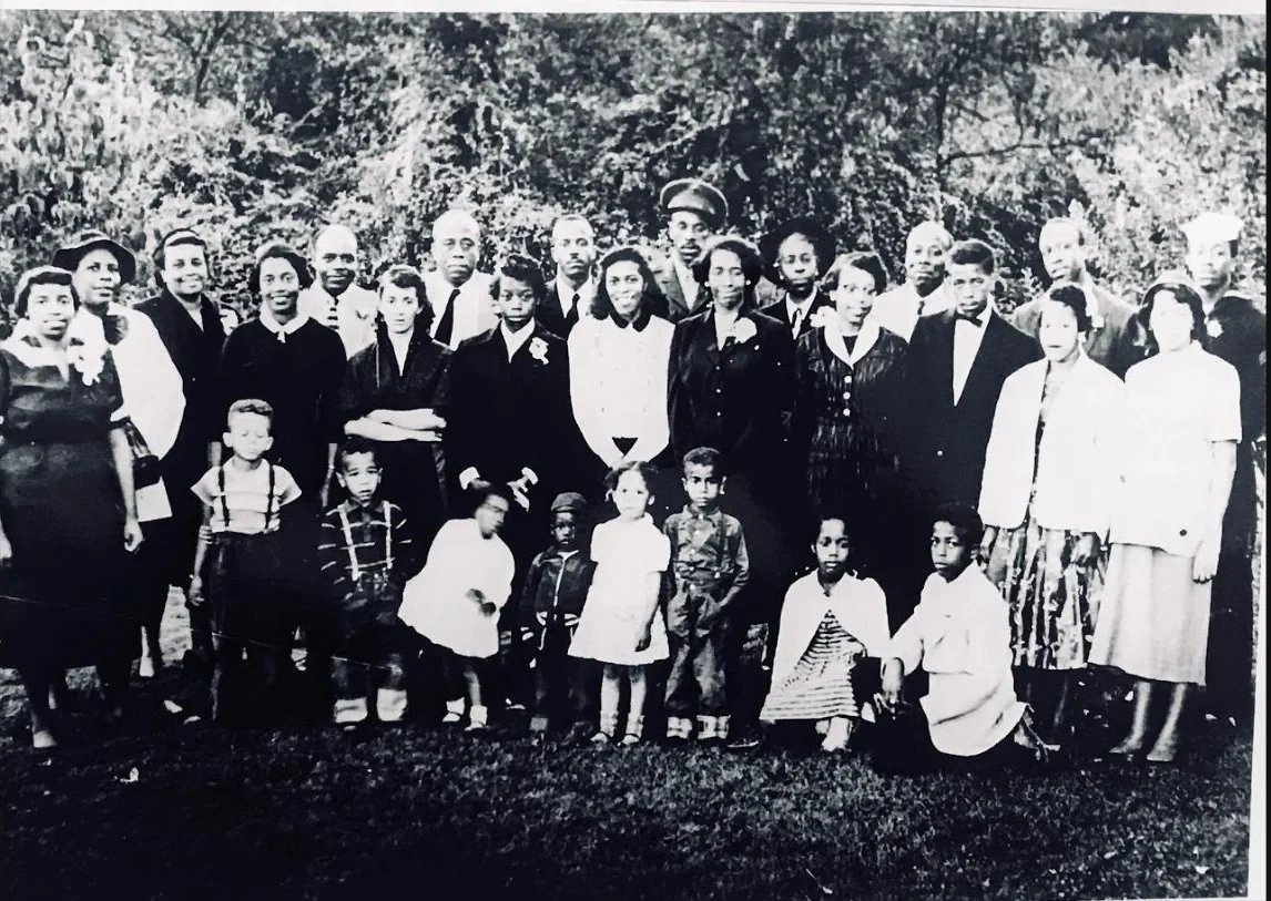 A mid-century black and white photograph of the Cash-Neill family gathered outdoors in their Sunday best
