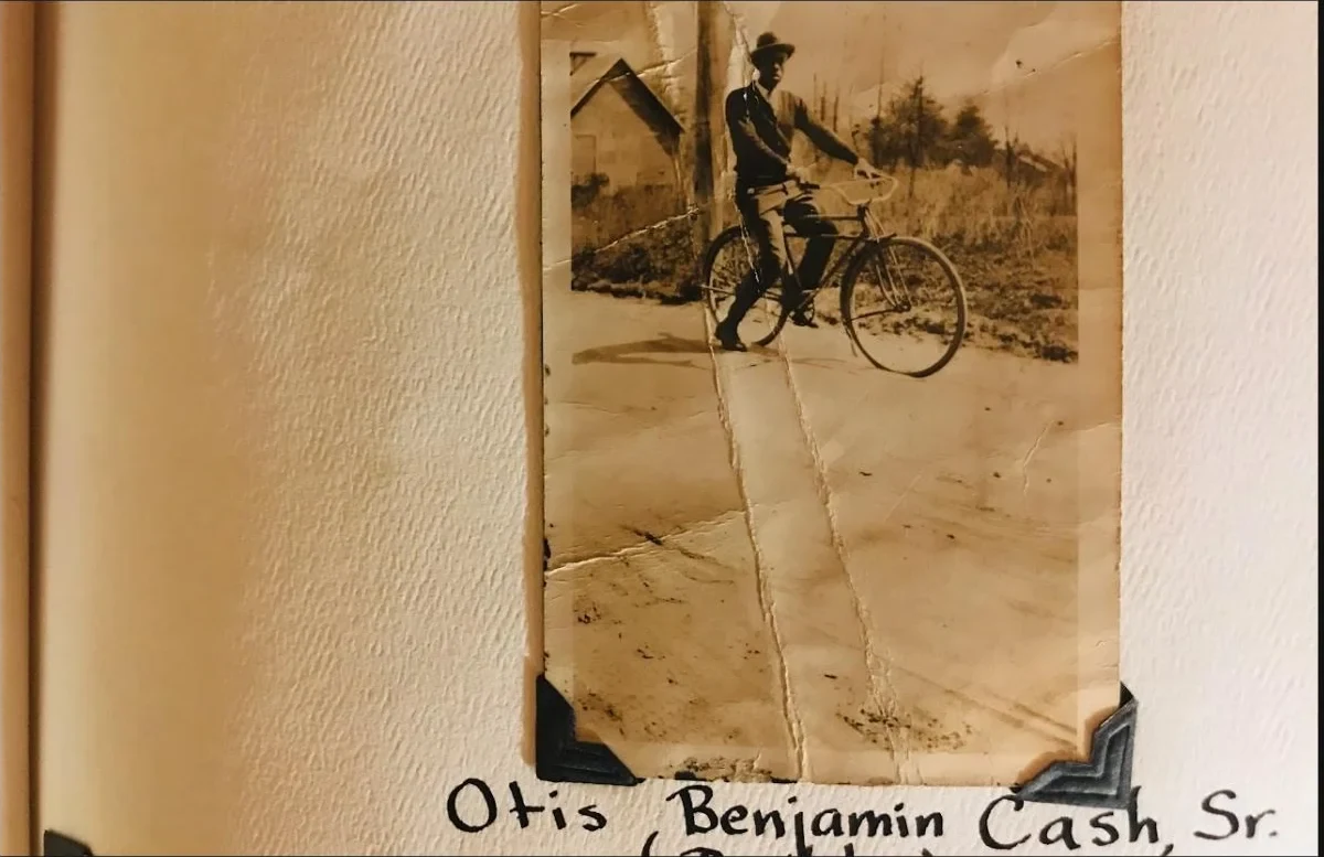 A family album page showing Otis Benjamin Cash, Sr. beside his bicycle with his name handwritten below
